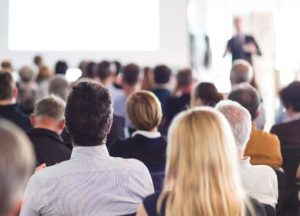 A conference audience attentively listens to a speaker during an RTO training event.