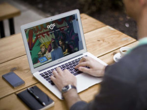 A person works on a laptop at an outdoor cafe, demonstrating how RTO Training Group supports flexible training solutions.