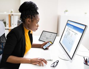 A woman uses multiple devices for online banking, highlighting assessment methods in online learning.