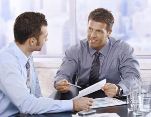 Businessmen reviewing charts and documents during a meeting, highlighting the value of constructive feedback.