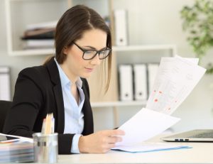 A businesswoman reviews AQF documentation at her desk, focusing on VET sector updates.