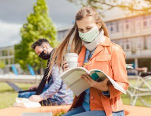 Students wearing face masks study outside on a university campus, reflecting changes to the vet sector due to COVID-19.