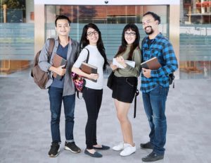 University students with books discuss learning, highlighting the need for reasonable adjustments.