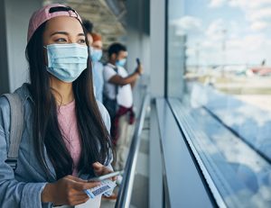 A masked woman views the airport, reflecting strong international student arrivals in Australia.