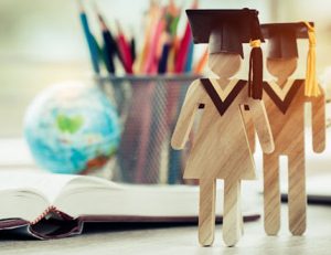 Graduation-themed wooden figures represent issuing qualifications to trainers and staff.