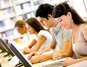 Students researching with computers and books, demonstrating effective e-learning.