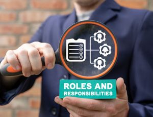 A business professional reviews roles and responsibilities with a magnifying glass, highlighting the importance of trainer.